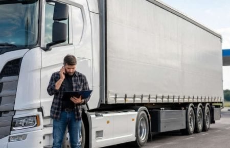 Șofer coordonând un transport lângă o semiremorcă